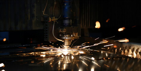 Sparks fly out machine head for metal processing laser metal on metallurgical plant background....