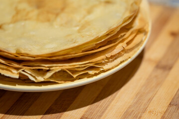 Just fried delicious crepes with crispy edges on a white plate, close up. Tasty pancakes, homemade sweet food