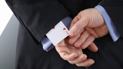 Close-up of cheater hands pulling ace card out of sleeve with crossed arms behind. Gamer with...