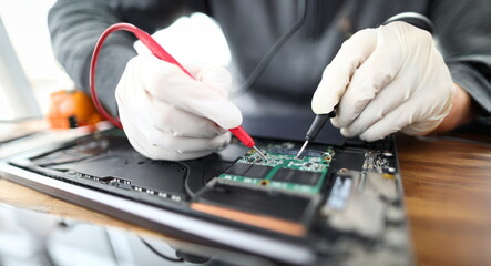 Close-up of male professional working with instruments and tools. Technician wearing protective gloves fixing personal computer circuit board. Gadgets support and maintenance