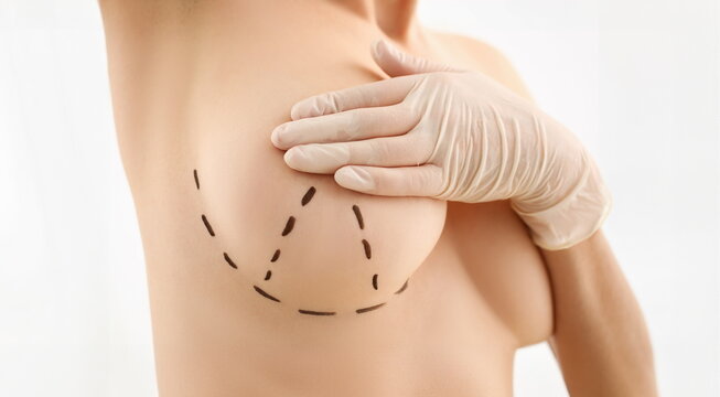 Female hand in gloves holding breast closeup on doctor mammology clinic reception. Mammary glands test biopsy implant silicone insert tumor human concept