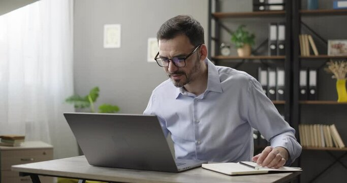 Smiling man using laptop computer, making notes at home office. Corporate training, virtual meeting, study with online tutor teacher, advanced adult learning course, remote study