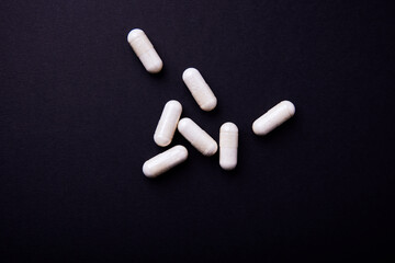 Creatine capsules on dark paper background. Soft focus. Close up. Copy space.	