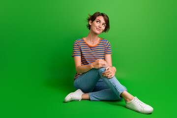 Full body portrait of gorgeous creative minded lady sit floor look empty space isolated on green color background