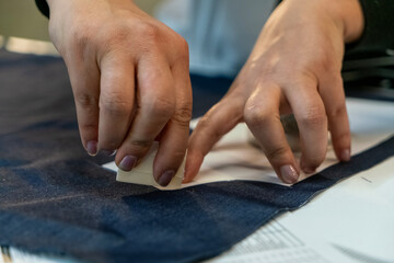 Obraz premium Close up view of tailor's hand marking sewing pattern on fabric with soap.