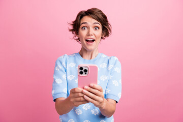 Photo of astonished positive lady hold smart phone open mouth cant believe isolated on pink color background