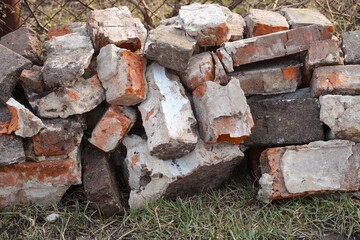 A pile of broken old bricks lying in front of a chain link fence.