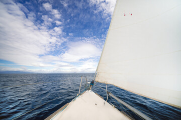 A gleaming white yacht sails on calm waters. Mountains are visible on the horizon. Traveling on a sailing yacht. Sailing.