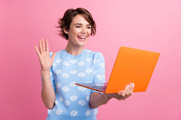 Portrait of attractive cheerful lady arm palm waving communicate video call laptop isolated on pink...