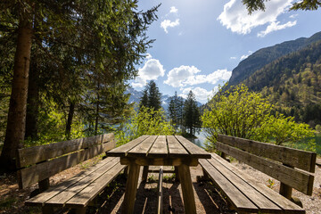 Picnic table on the shore of a sunny alpine lake with a nice view of a tiny island in the lake.