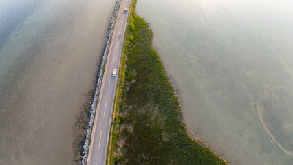 Aerial photo high above the cars driving on a road crossing a lagoon.