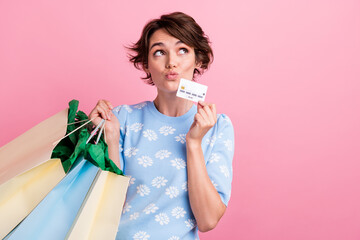 Portrait of charming creative person hold mall bags debit card look empty space isolated on pink...