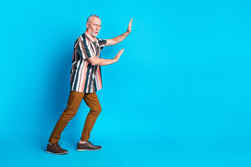 Photo of strong man pensioner man wear striped stylish clothes push empty space isolated on blue color background