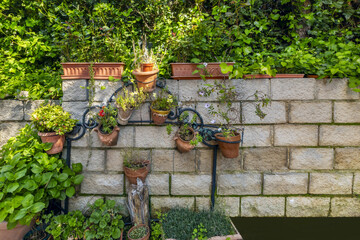 Brick wall of a perimeter garden with pots of decorative plants