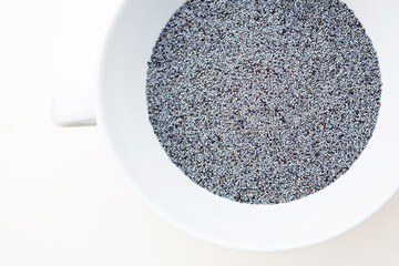 Close-up of organic blue poppy seeds in a white bowl with handle