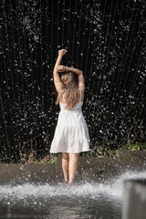 woman standing barefoot in falling water fountain - obrazy, fototapety, plakaty