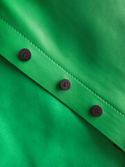 Close-up detail of green leather jacket, buttons and stitching