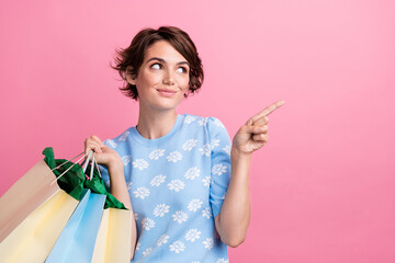 Photo of attractive person hold store shop bags look direct finger empty space isolated on pink...