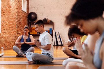 A group of multiethnic athletes sit on mats and meditate. The end of fitness classes and relaxed...