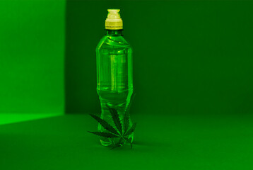 A mock-up of a transparent plastic bottle with a white lid with pure mineral water and a green cannabis leaf. Bottle layout and hemp.