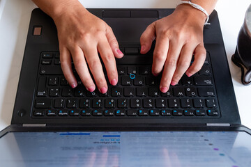 A person is typing on a laptop keyboard