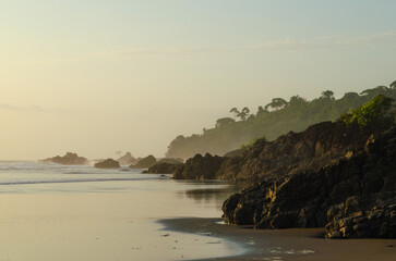 Sunset on coastline with rocks and jungle