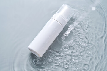 Bottles of cosmetic products in water on a blue background.