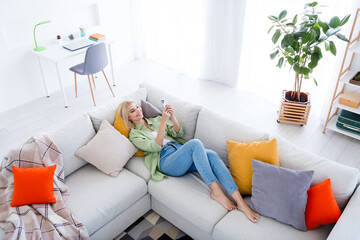 Photo of cute cheerful pretty girl lying on comfortable sofa spending vacation alone sunny white...