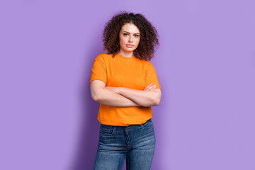 Photo of serious confident woman wear orange t-shirt arms folded isolated purple color background