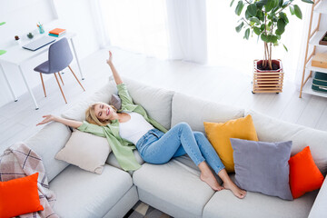 Photo of positive good mood girl lying on couch with raised hands buy real estate own cottage enjoy...
