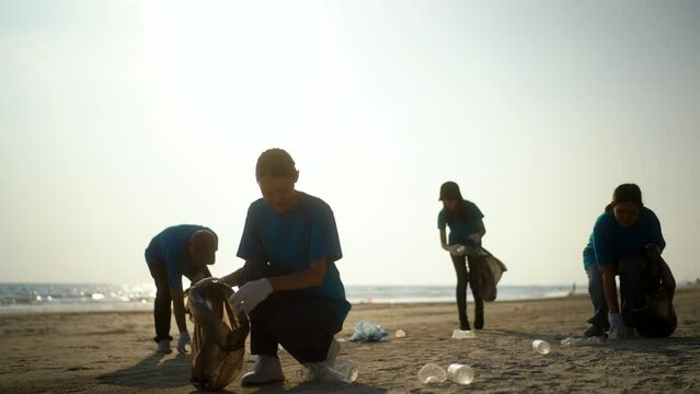 Teamwork moment of volunteer people group in volunteering charity activities cleaning up waste plastic on sand sea ocean beach . Corporate social responsibility and society activity for Environment.