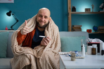 Happy patient recovered from flu holding thermometer showing class gesture to camera