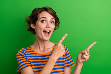 Photo portrait of lovely young lady excited point empty space dressed stylish striped garment isolated on green color background