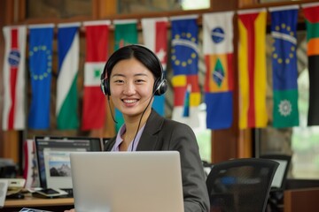 a professional woman with a pleasant smile wearing a headset, seated at a desk with an open laptop