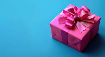 Obraz premium Fuchsia color wrapped present box with ribbon bow on it. Vivid blue background with place for text on left side. Happy Holidays or Shopping Sale.