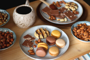 Cup of tea or coffee, cookies, macaroons, chocolate, various nuts and cocoa powder on wooden table. Selective focus.