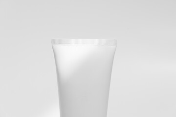 Close-up of the top of a tube of cream illuminated by the sun on a white isolated background. Concept of beauty and cosmetic products. Image for your design