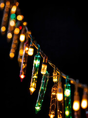 Shimmering LED Christmas lights strung along a garland, creating a magical ambiance against a black backdrop.