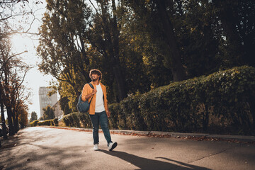 Photo of cheerful glad young man wear stylish clothes walking spending weekend enjoying sunny weather morning outside