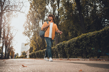 Portrait of nice glad funny man traveler pedestrian dressed trendy clothes walking in park looking around