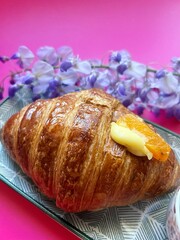 artisan croissant, fresh crispy croissant, puff pastry croissant, cornetto with cream, purple wisteria, pink background
