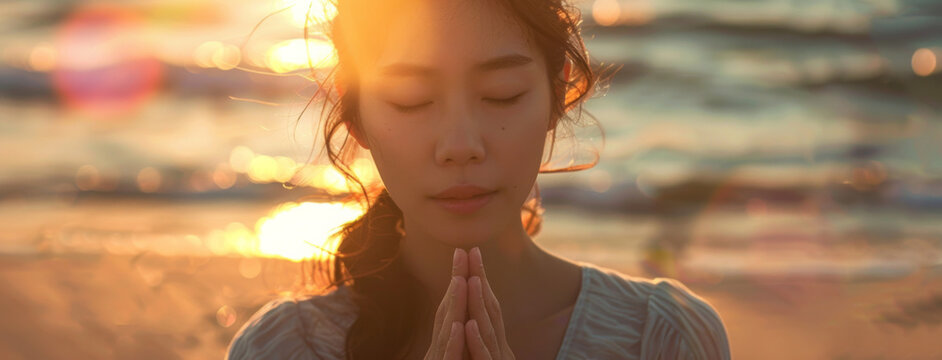Asian woman, peace and beach with praying at sunset for spiritual, worship in nature for meditation. Female person, calm and ocean with hands for God in banner, faith and mindfulness with prayer