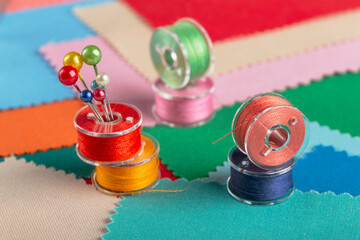 sewing kit, bobbins with colored threads and hairpins. Background from colored scraps of fabric.