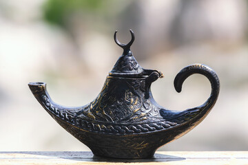 Elegant antic black Turkish genie lamp, ornately detailed, isolated on a soft blurred background,...