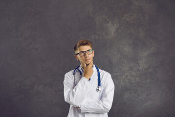 Serious young Caucasian male doctor in white medical uniform think of good medicine service....