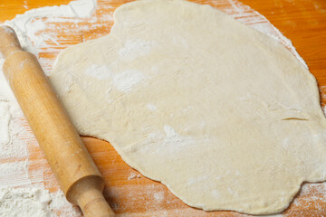 There is rolled out dough and a rolling pin on the table sprinkled with flour
