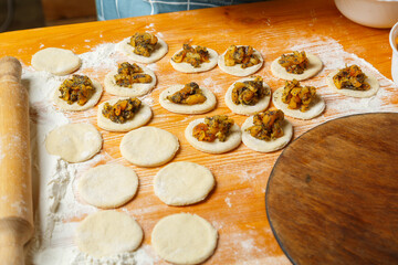 Blanks for sweet gomentashi cookies on the table in flour next to dried fruits