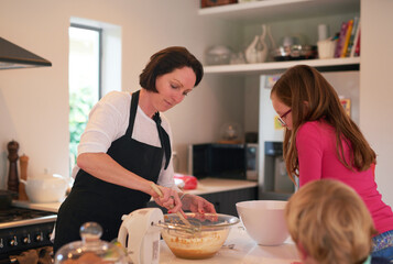 Mother, children and baking in kitchen in home, family and bonding together with mixing machine on...