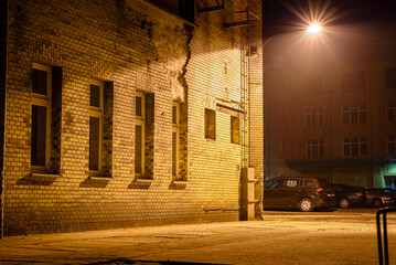 A lantern attached to an industrial building and glowing, a lantern on a house wall, light fog,...