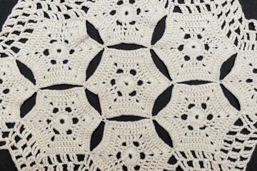 Vintage handmade white knitted napkin isolated on a black background.